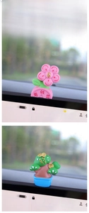 Close-up of cute fortune flower and pine tree car dashboard figurines for wealth