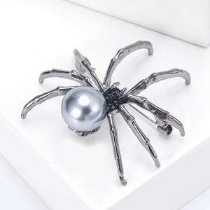 Close-up of spider brooch featuring a large grey pearl and dark metal rhinestone legs