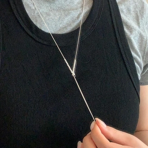 Detail of minimalist S925 sterling silver ball bead V-shape necklace worn on model