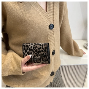 Primo piano di una mini borsa a busta con stampa leopardata tenuta in mano