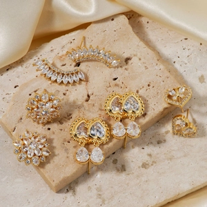 Elegant gold earrings set with cubic zirconia on a minimalist stone background