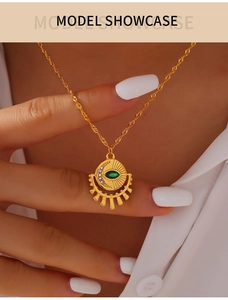 Detail of vintage gold necklace featuring a green marquise gem and sunburst moon pendant