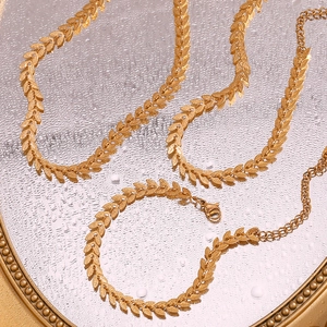 Detail showing gold leaf pattern necklace and bracelet set on a textured surface