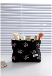 Detail view of black floral embroidered makeup bag showing storage space with brushes