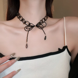 Detail of black glass beaded necklace featuring a large bow pendant and teardrop charms