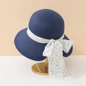 Détail d'un chapeau de paille bleu marine avec ruban floral sur support doré élégant