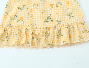 Dettaglio dell'abito a quadri con stampa di limoni e bordo in pizzo delicato sull'orlo