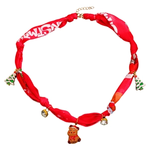 Détail d'un collier en soie rouge avec breloques sapin de Noël et élan sur blanc