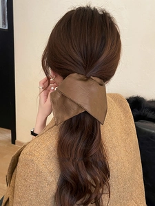 Detailed back view of a model wearing a brown leather bow hair tie for high ponytails