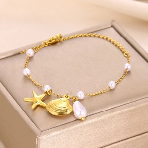 Detailed shot of gold starfish and shell charms with pearls on a nautical charm bracelet