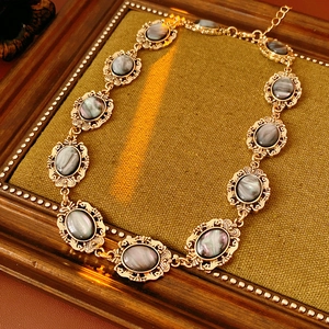 Close-up of vintage golden necklace with grey oval resin stones on green fabric