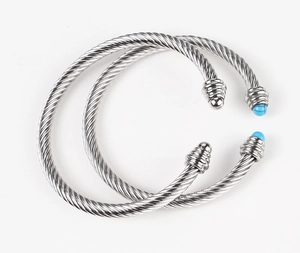 Detail of twisted cable cuff bracelets in silver steel with turquoise stone bead accents