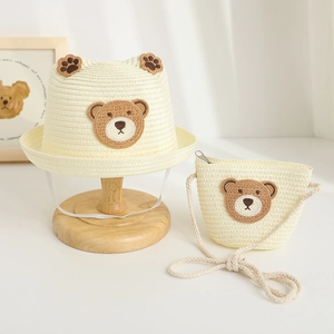 Detail of baby straw sun hat and matching small shoulder bag with cute bear embroidery