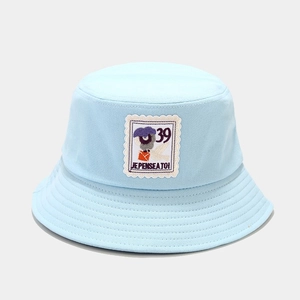 Detail of light blue cotton bucket hat featuring a vintage stamp patch and clean stitching