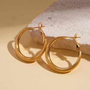 Detail of 18k gold-plated thick hoop earrings on a textured stone display