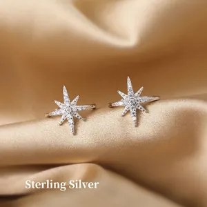 Minimalist silver star ear cuff with zircon stones on golden silk background