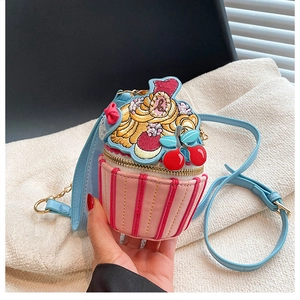 Detail of cupcake-shaped crossbody bag with cherry embroidery and chain strap