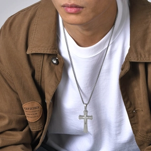 Male model wearing silver triple-layer cross pendant necklace on brown jacket