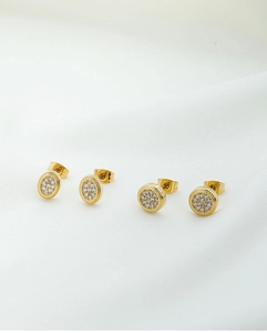 Macro detail of gold-plated square star stud earrings with pave zircon on silk fabric
