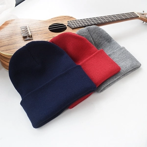 Mise à plat de bonnets en tricot en bleu marine, rouge et gris sur fond blanc