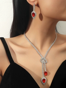 Close-up of bridal jewelry set with red teardrop gemstones and sparkling rhinestones
