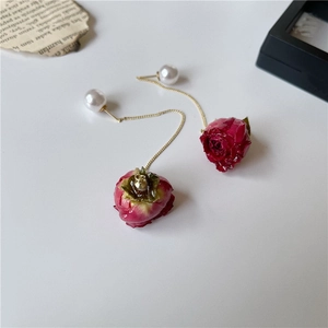 Detailed close-up of long rose drop earrings with gold chain and white pearl studs