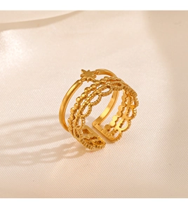 Detail of layered gold ring with star accent and lace pattern on beige silk background
