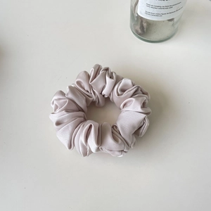 Detail of champagne pink satin scrunchie showing elegant pleated texture and soft silk luster