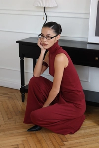 Close-up of burgundy sleeveless turtleneck and knit pants showing drape and texture