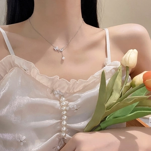 Detail of silver butterfly pendant necklace with sparkling crystals and a white pearl charm