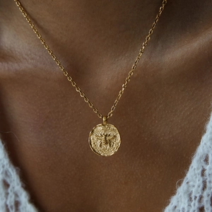 Elegant gold titanium necklace with bee pendant and freshwater pearl on female model