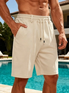 Detail of men's beige waffle knit shorts featuring texture and drawstring waist by the pool