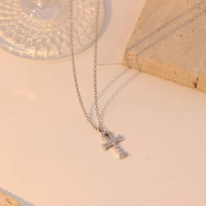 Silver stainless steel Ankh cross necklace with white zircon pavé on smooth stone surface