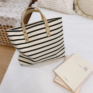 Detail of striped canvas tote with quilted texture and premium leather handles
