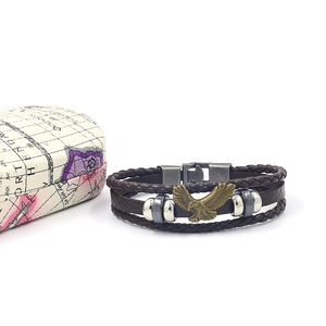 Dettaglio del bracciale multistrato in pelle con aquila e perline su scatola vintage