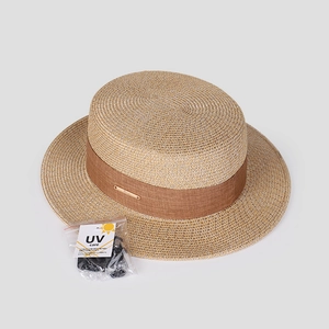 Détail d'un chapeau de paille tressé avec ruban marron et cordon coupe-vent amovible
