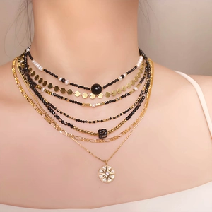 Layered gold necklace with black spinel beads, pearls, and a vintage starburst pendant