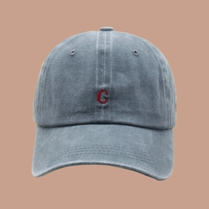 Close-up of red letter C embroidery on washed blue cotton baseball cap with vintage texture