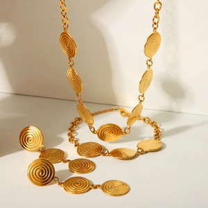 Detailed view of gold spiral textured necklace and earring set on minimalist background