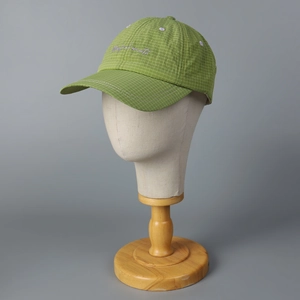 Detail of green plaid baseball cap featuring purple cursive embroidery on crown