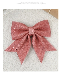 Close-up of glittery pink Christmas bow decoration on soft white faux fur background