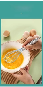 Close-up of sky blue silicone whisk mixing eggs in a white bowl with stainless handle