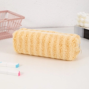 Close-up of fluffy yellow plush pencil case with zipper on a desk with stationery