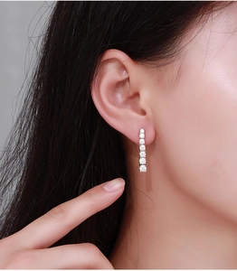 Close-up of elegant silver moissanite tassel earrings worn on a model with soft lighting
