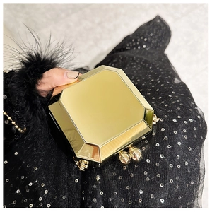 Close-up of golden geometric octagonal clutch bag with spherical metal clasp