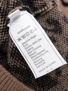 Detail of care label on leopard print knit sweater showing 100% polyester and washing instructions