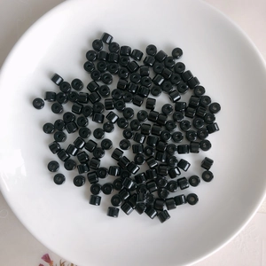 Macro view of polished black cylindrical acrylic spacer beads scattered on a white tray