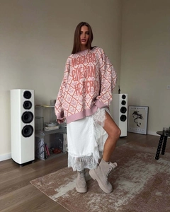 Detail of pink knit sweater with white lace skirt and beige boots in modern home setting
