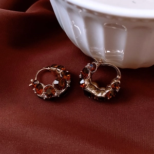 Detailed shot of vintage gold-plated round earrings with amber gemstones on fabric