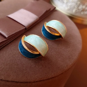 Macro view of C-shaped vintage earrings with mint green and navy blue enamel finish